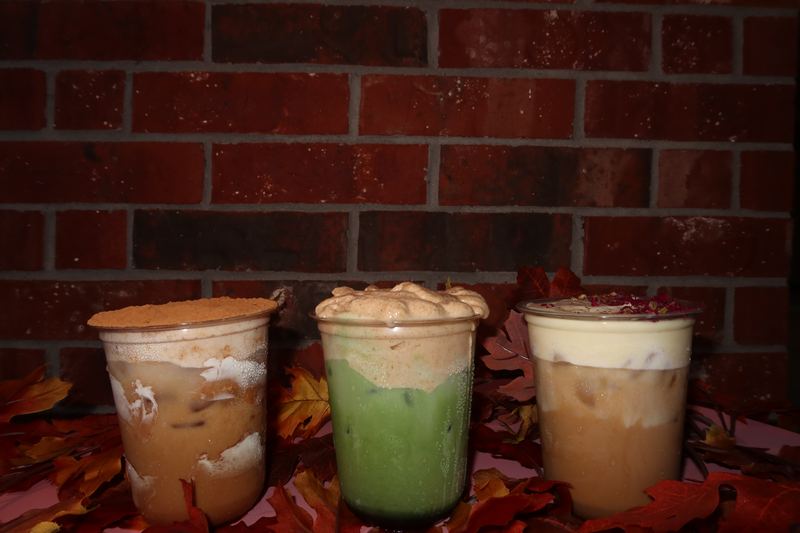 Three iced drinks lined up in front of a brick wall