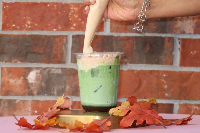 Foam being piped onto an iced matcha