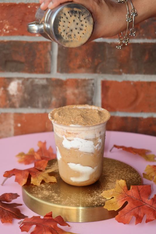 Spice being dusted over a layered iced drink
